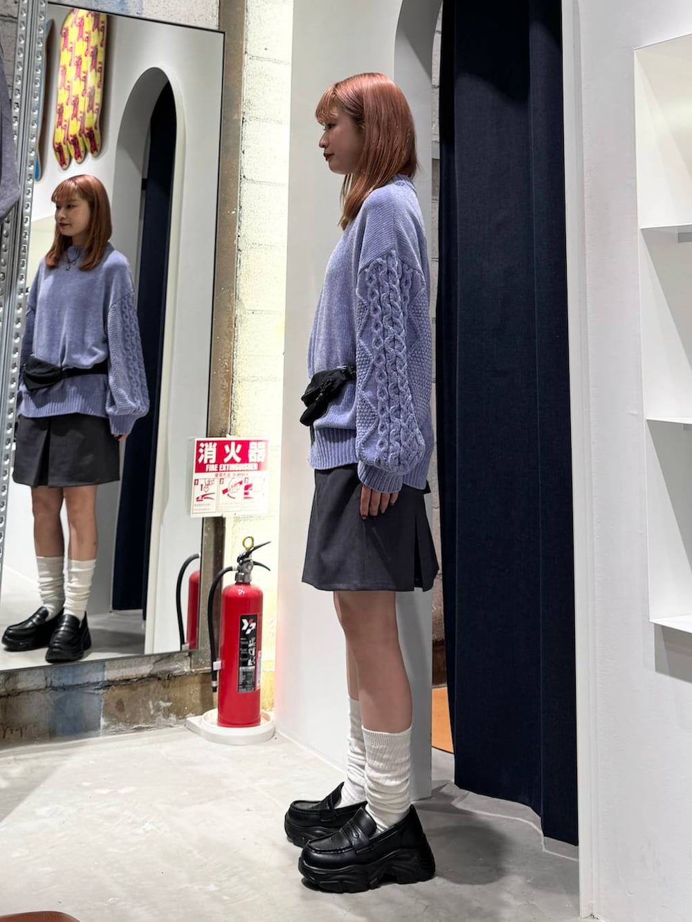 ブルー系のニット/セーター、グレー系のスカート、ブラック系のボディバッグ/ウエストポーチを着用したレディースの秋コーディネートの5枚目の写真