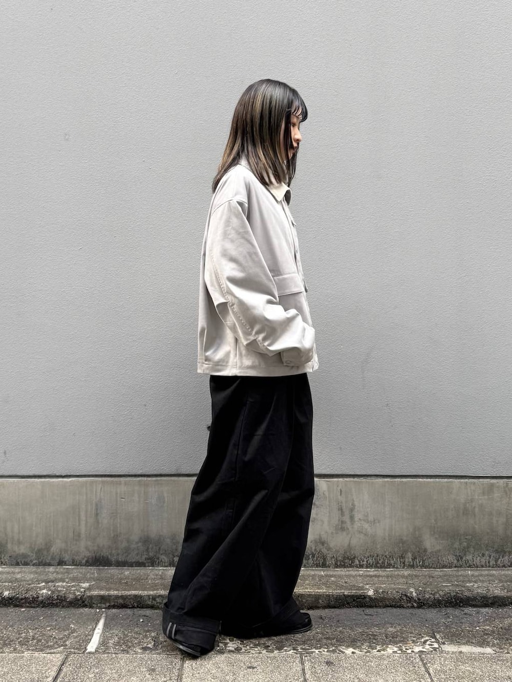 グレー系のブルゾン、ブラック系のチノパンツを着用したレディースの春コーディネートの6枚目の写真
