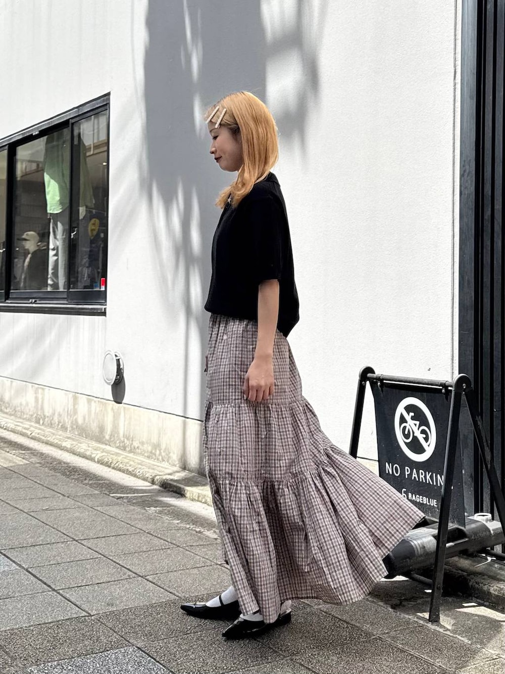 ブラック系のパンプス、ブラック系のポロシャツ、ベージュ系のスカートを着用したレディースの春コーディネートの5枚目の写真