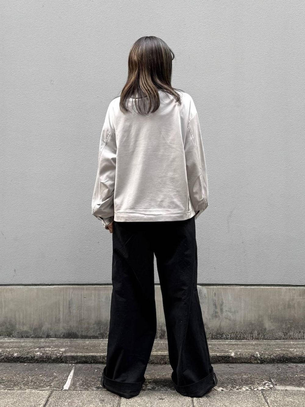 グレー系のブルゾン、ブラック系のチノパンツを着用したレディースの春コーディネートの5枚目の写真