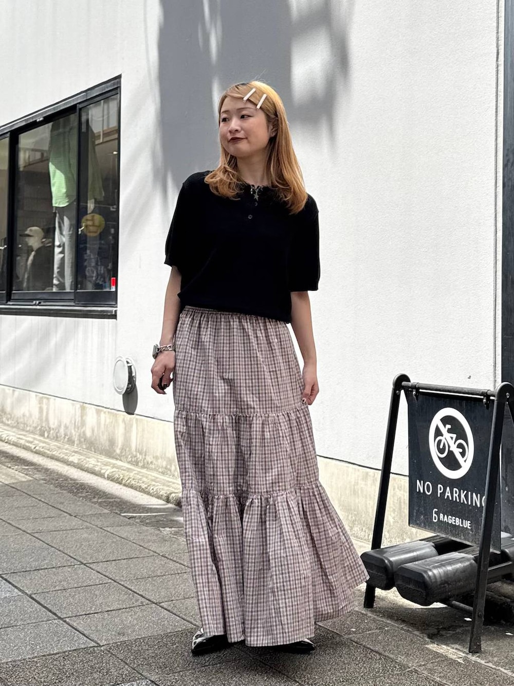 ブラック系のパンプス、ブラック系のポロシャツ、ベージュ系のスカートを着用したレディースの春コーディネートの4枚目の写真