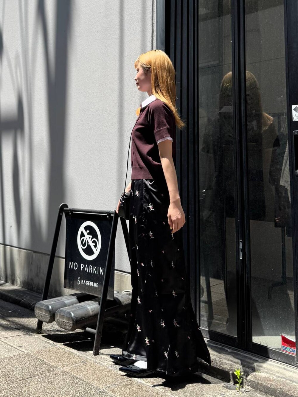 ブラック系のパンプス、ブラック系のスカート、ブラック系のショルダーバッグを着用したレディースの夏コーディネートの5枚目の写真