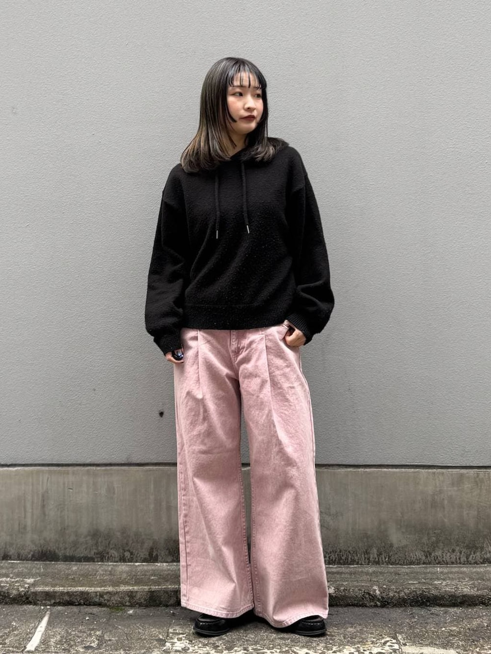 ピンク系のデニムパンツ、ブラック系のニット/セーターを着用したレディースの春コーディネートの2枚目の写真