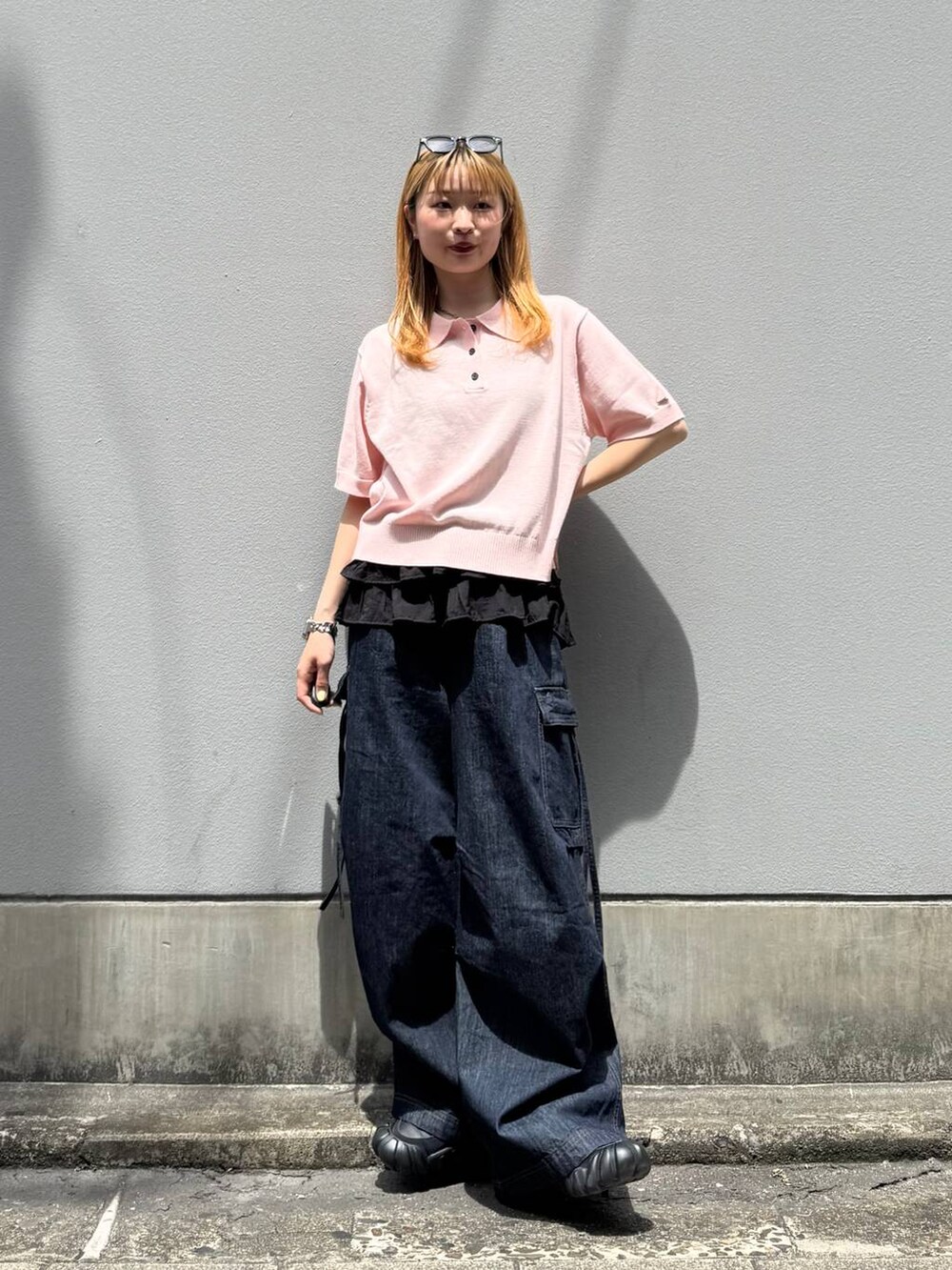 ピンク系のポロシャツ、ブルー系のデニムパンツ、グレー系のタンクトップを着用したレディースの夏コーディネートの2枚目の写真