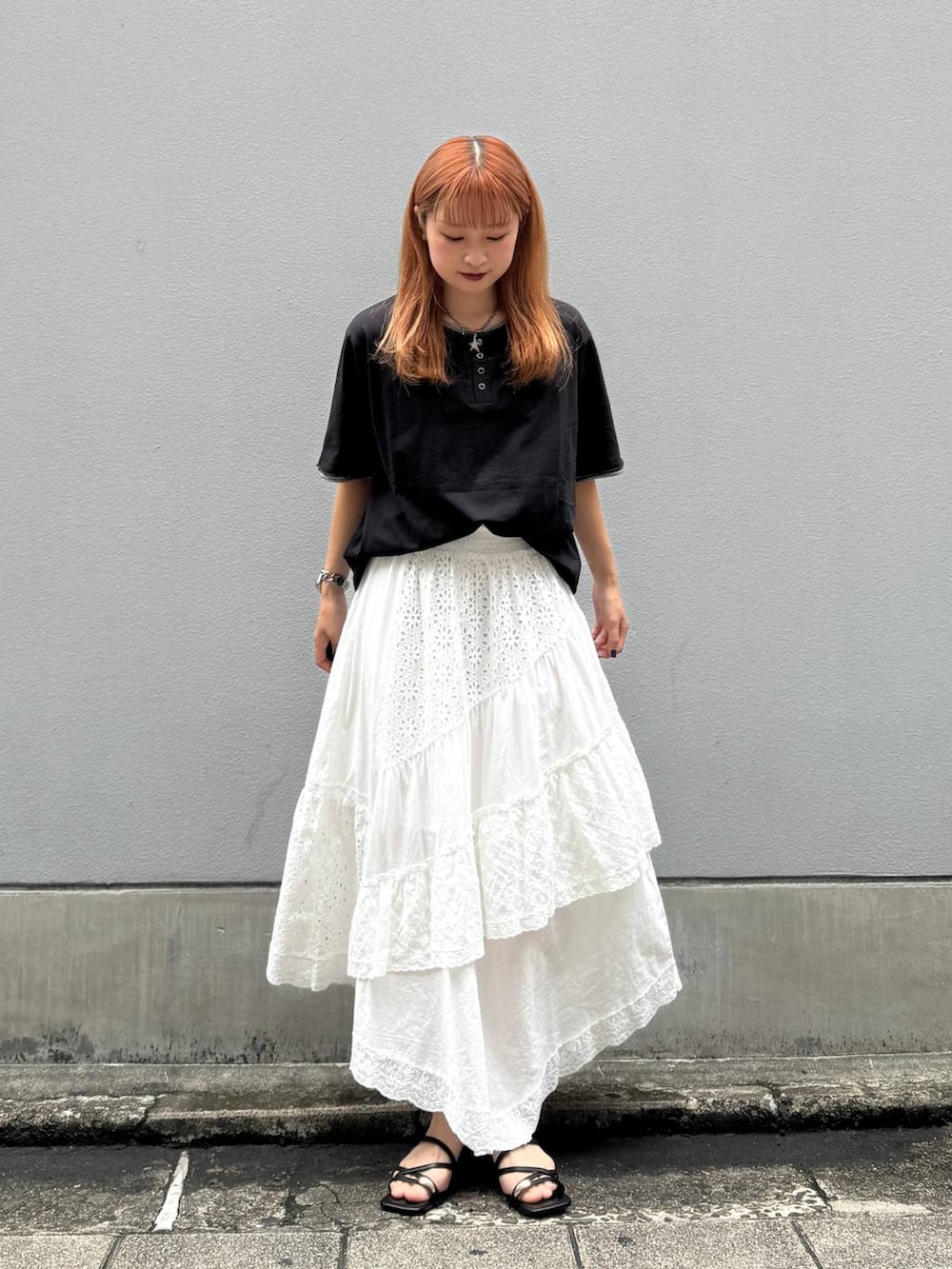 ホワイト系のスカート、ブラック系のTシャツ/カットソー、ブラック系のサンダルを着用したレディースの夏コーディネートの2枚目の写真