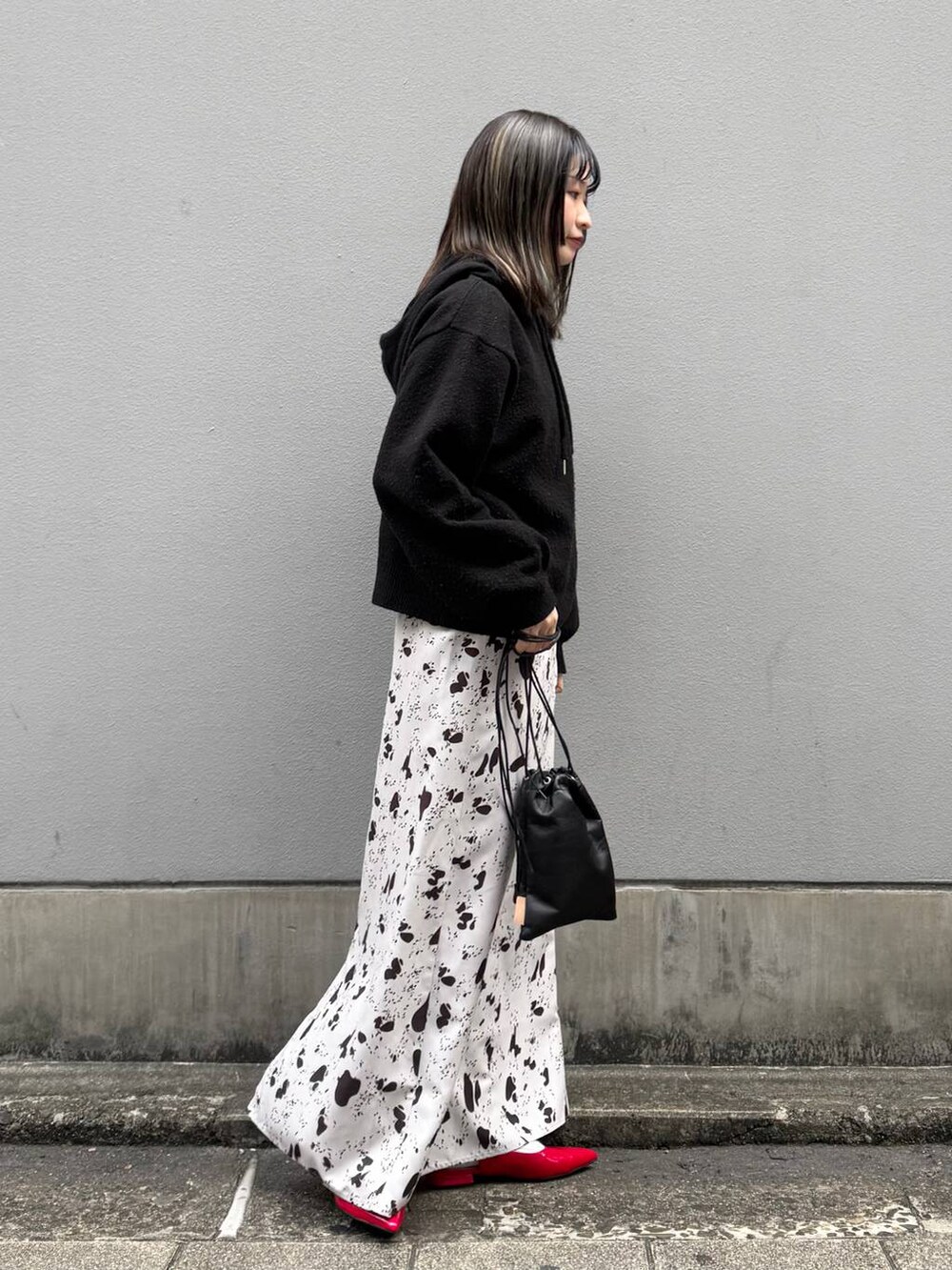 ブラック系のショルダーバッグ、レッド系のパンプス、ブラウン系のスカートを着用したレディースの春コーディネートの7枚目の写真