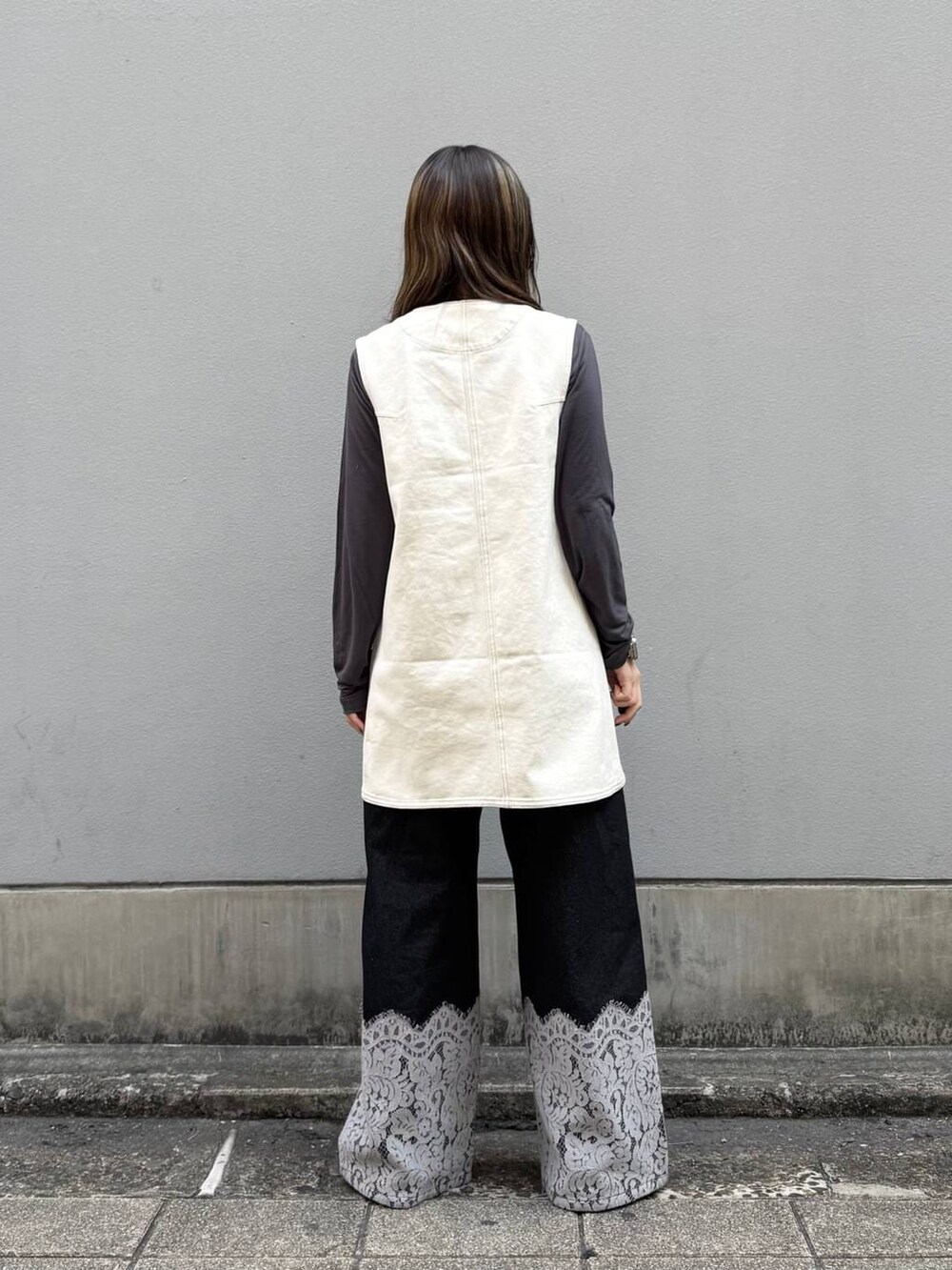 ブラック系のパンプス、ホワイト系のワンピース、ブラック系のデニムパンツを着用したレディースの春コーディネートの5枚目の写真