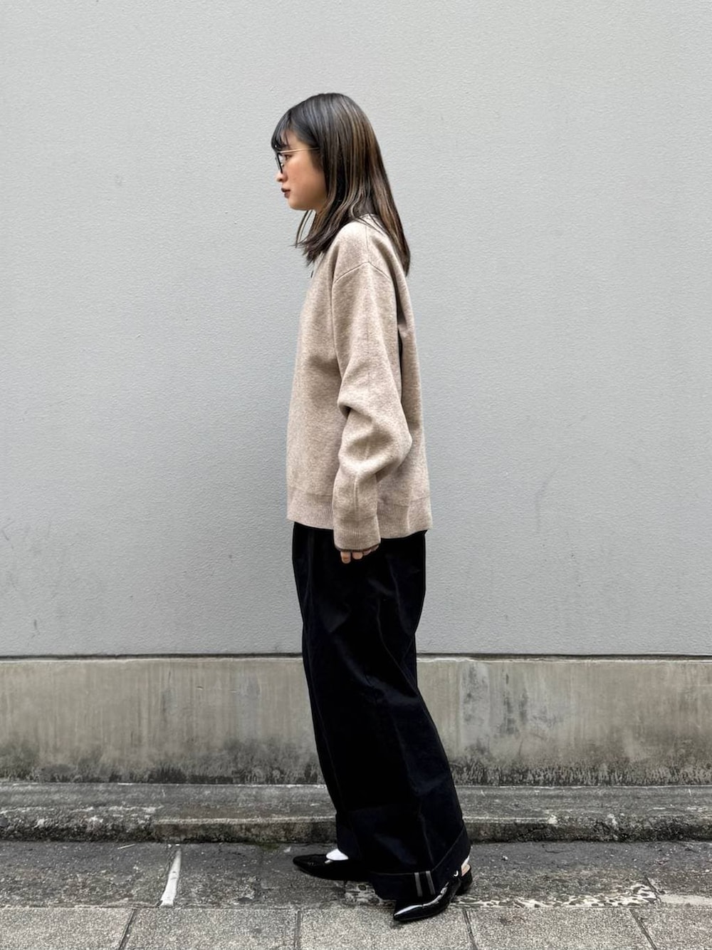 ブラック系のパンプス、ブラック系のチノパンツ、ベージュ系のニット/セーターを着用したレディースの春コーディネートの5枚目の写真