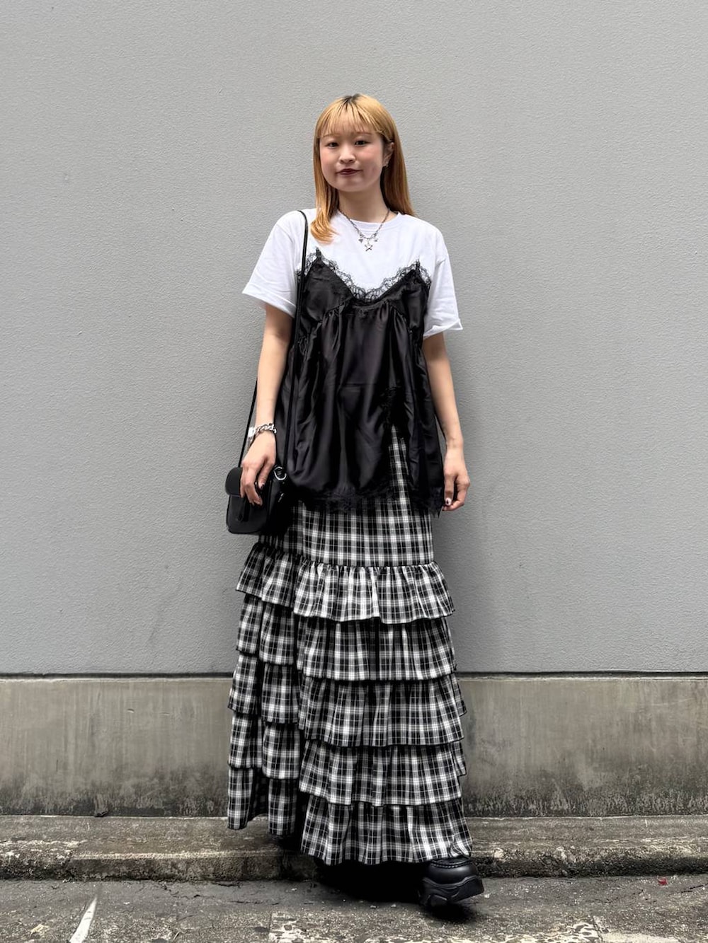 ブラック系のローファー、ブラック系のスカート、ブラック系のショルダーバッグを着用したレディースの夏コーディネートの4枚目の写真