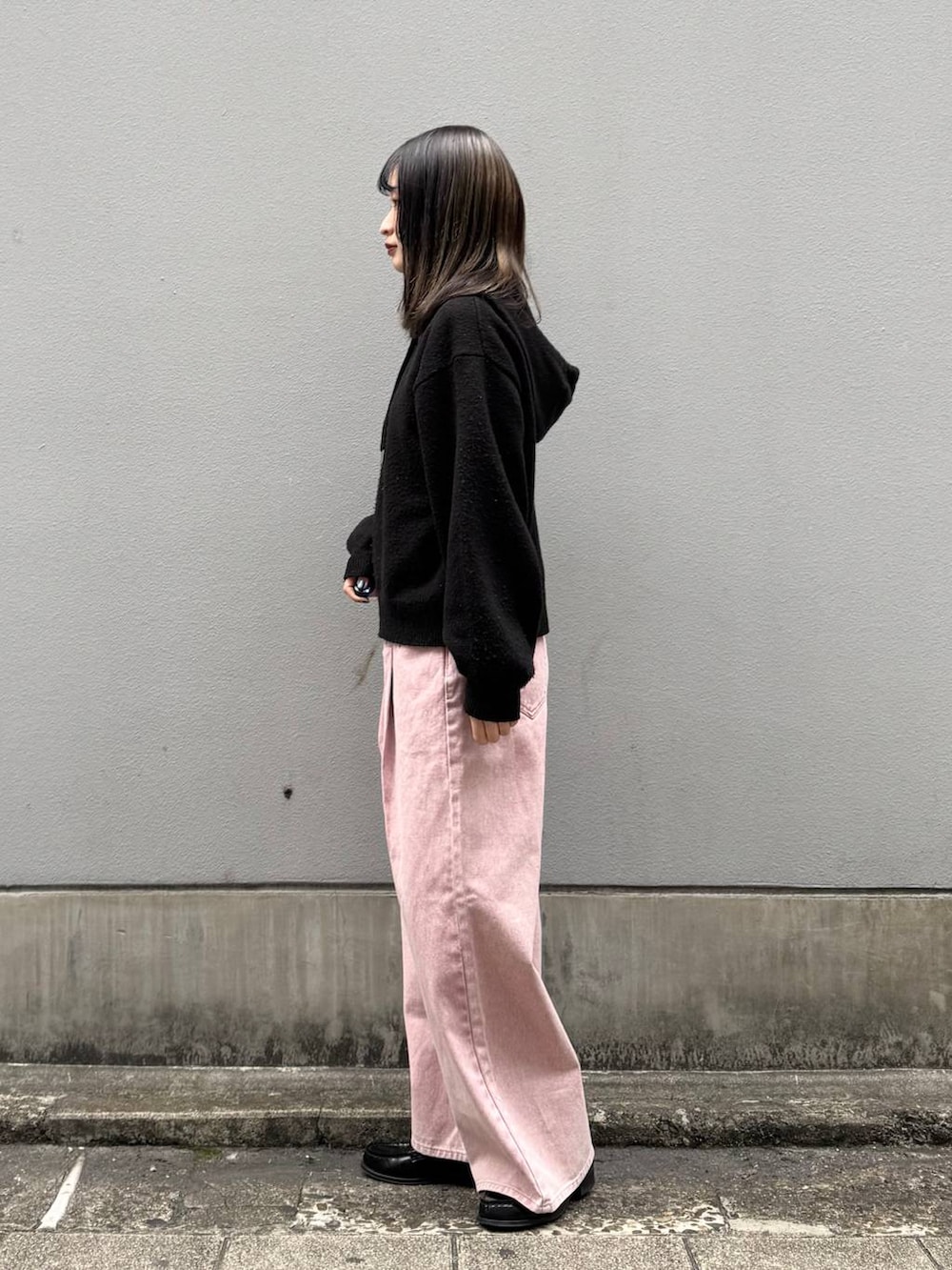 ピンク系のデニムパンツ、ブラック系のニット/セーターを着用したレディースの春コーディネートの5枚目の写真