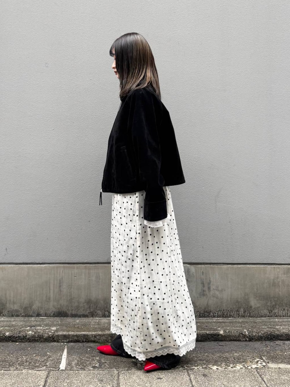 レッド系のパンプス、ブラック系のデニムパンツ、ブラック系のブルゾンを着用したレディースの春コーディネートの4枚目の写真