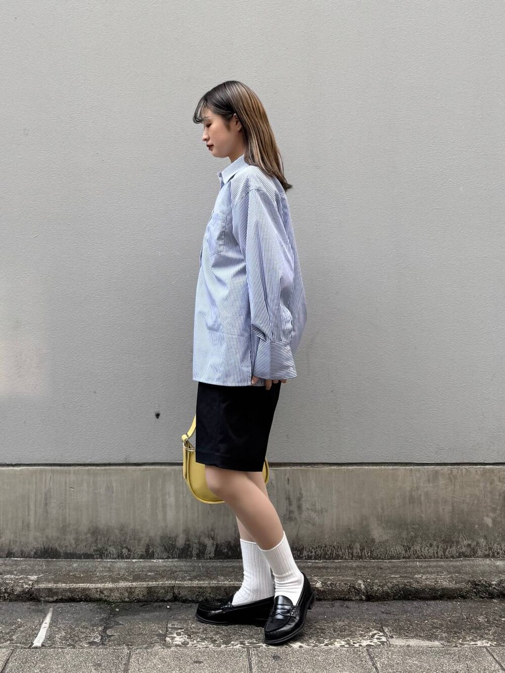 ブラック系のスラックス、イエロー系のショルダーバッグ、ブルー系のシャツ/ブラウスを着用したレディースの春コーディネートの4枚目の写真