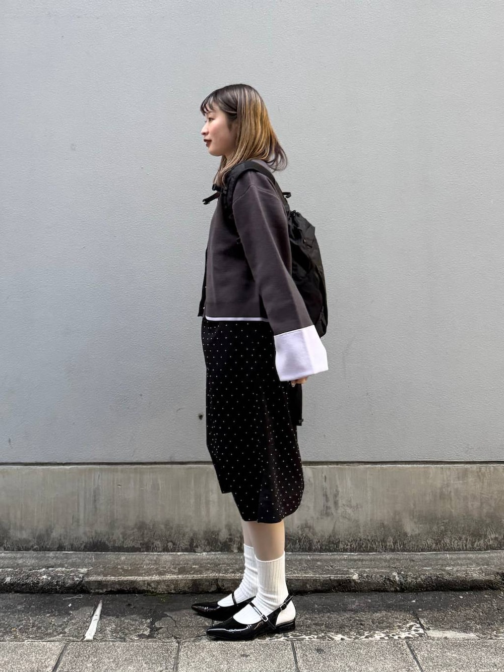 ブラック系のパンプス、グレー系のカーディガン/ボレロ、ブラック系のワンピースを着用したレディースの春コーディネートの5枚目の写真