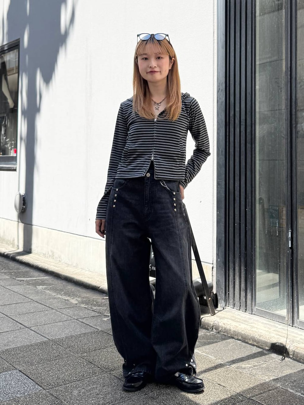 ブラック系のパーカー、グレー系のデニムパンツを着用したレディースの夏コーディネートの2枚目の写真
