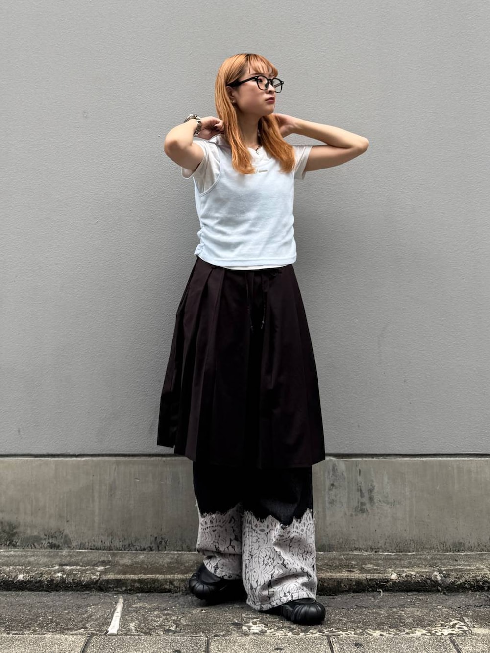 ブラウン系のスカート、ブラック系のデニムパンツ、ホワイト系のTシャツ/カットソーを着用したレディースの秋コーディネートの2枚目の写真