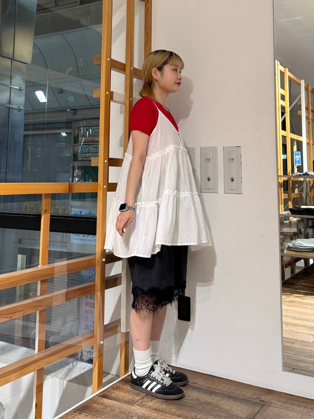 ホワイト系のチュニック、ブラック系のスラックス、レッド系のカーディガン/ボレロを着用したレディースの夏コーディネートの6枚目の写真