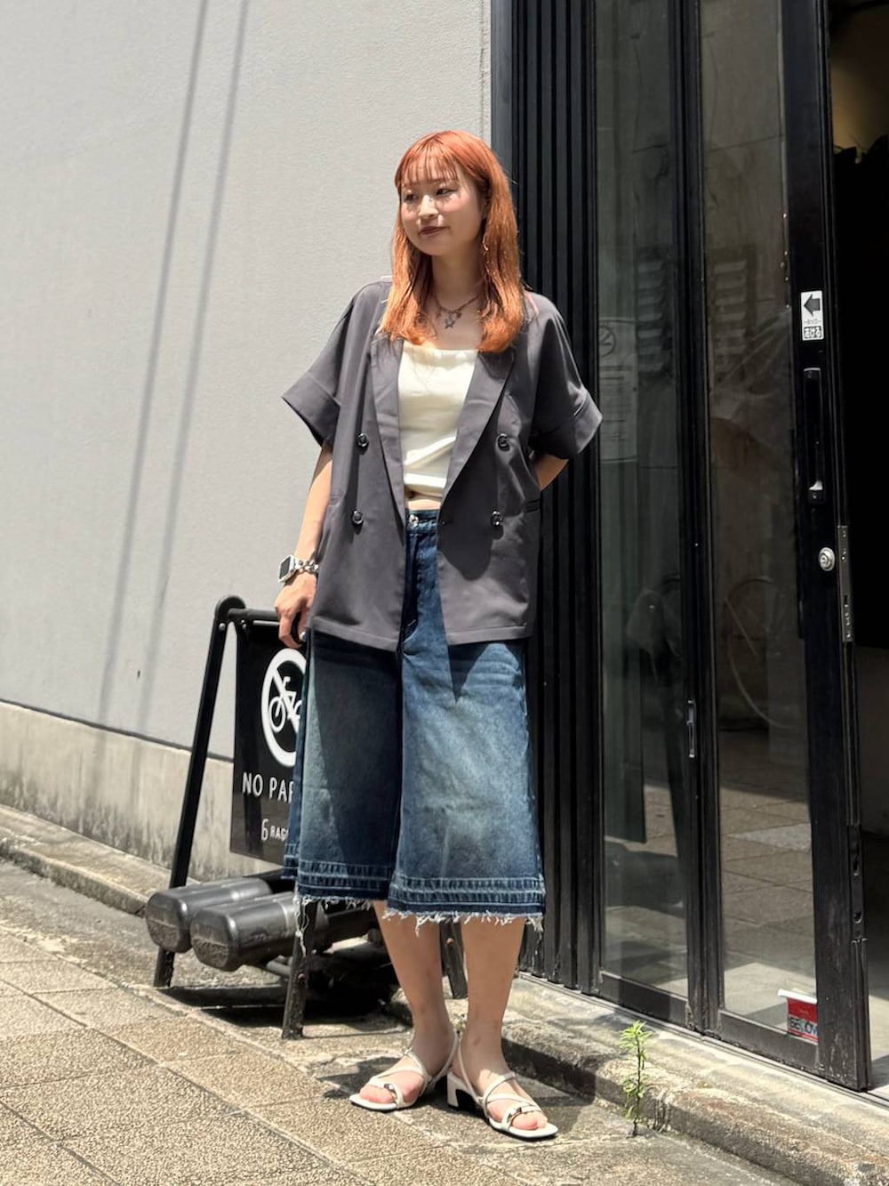 ブルー系のデニムパンツ、グレー系のテーラードジャケット、ホワイト系のキャミソールを着用したレディースの夏コーディネートの2枚目の写真