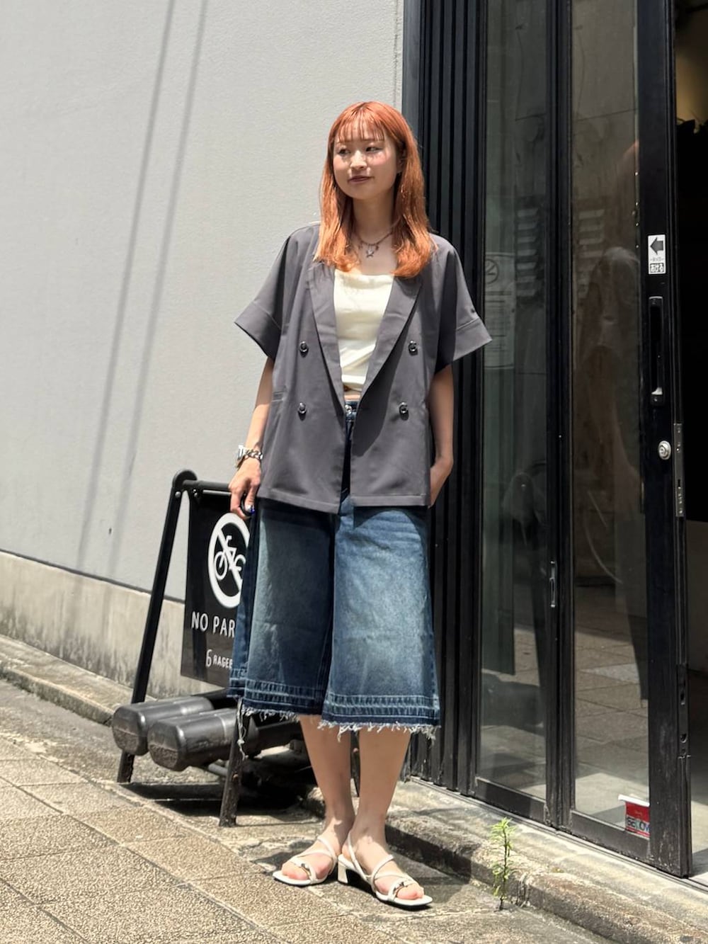 ブルー系のデニムパンツ、グレー系のテーラードジャケット、ホワイト系のキャミソールを着用したレディースの夏コーディネートの3枚目の写真