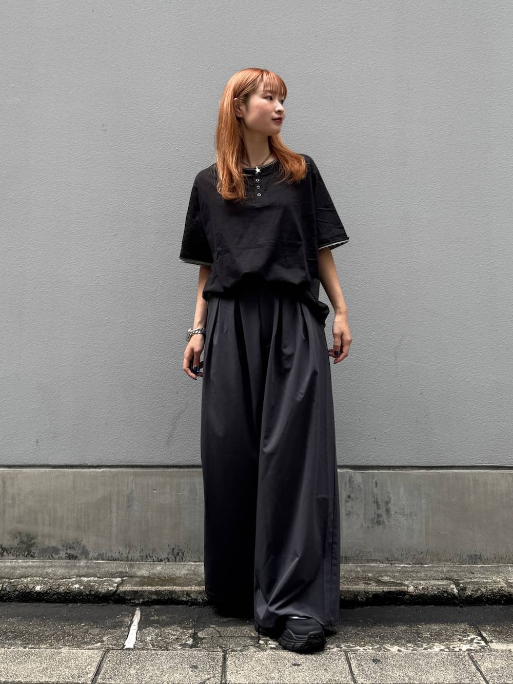 ブラック系のTシャツ/カットソー、グレー系のスラックス、ブラック系のサンダルを着用したレディースの夏コーディネートの3枚目の写真