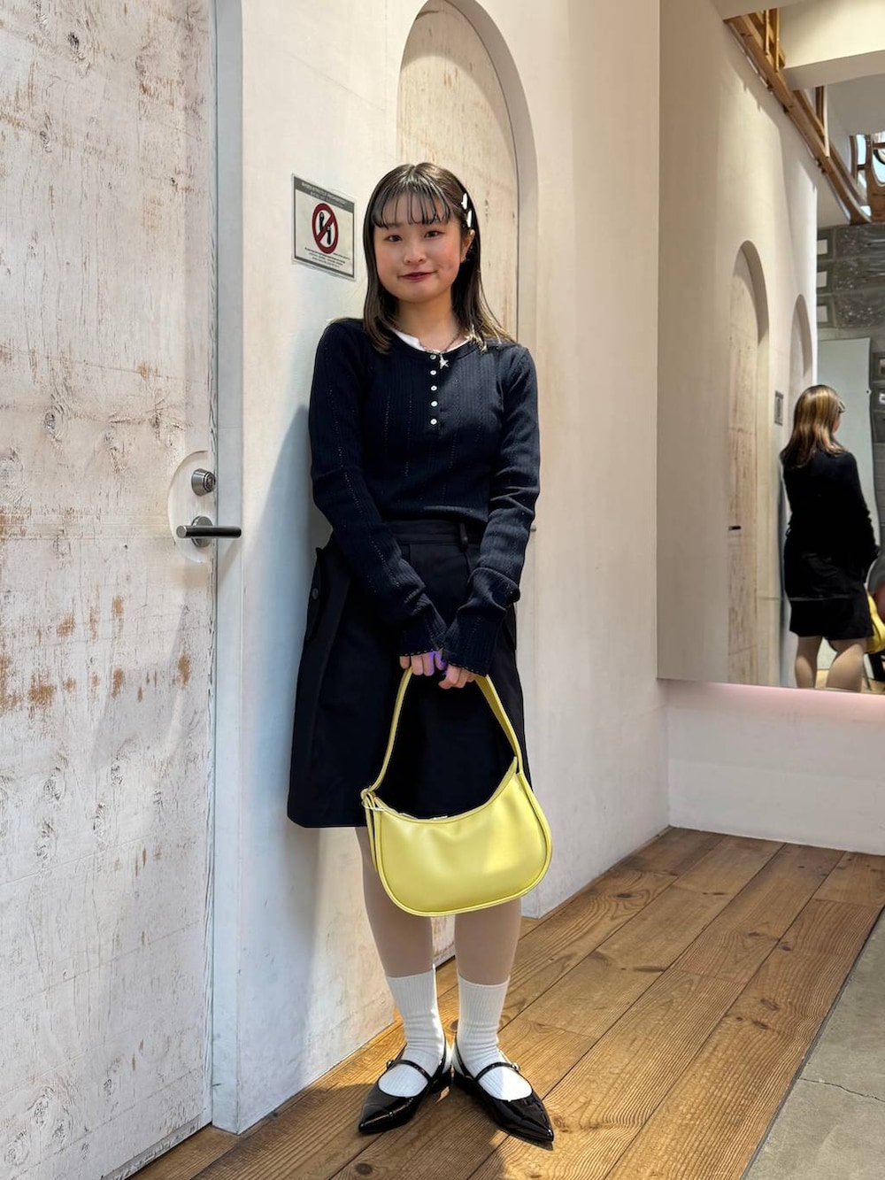 ブラック系のパンプス、ブラック系のスラックス、イエロー系のショルダーバッグを着用したレディースの春コーディネートの4枚目の写真