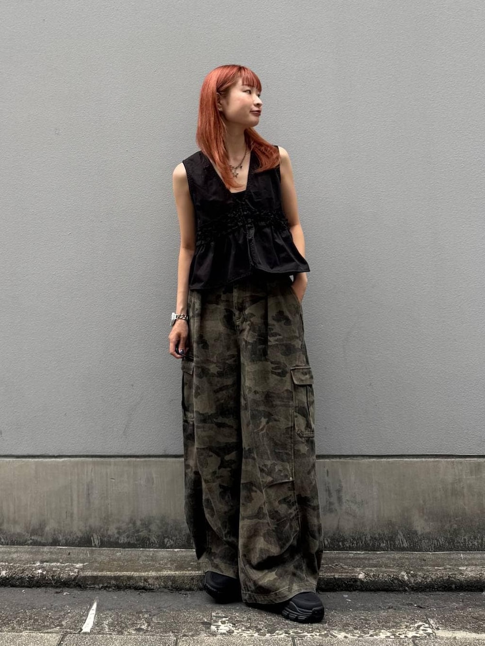 グリーン系のカーゴパンツ、ブラック系のタンクトップ、ブラック系のサンダルを着用したレディースの夏コーディネートの2枚目の写真