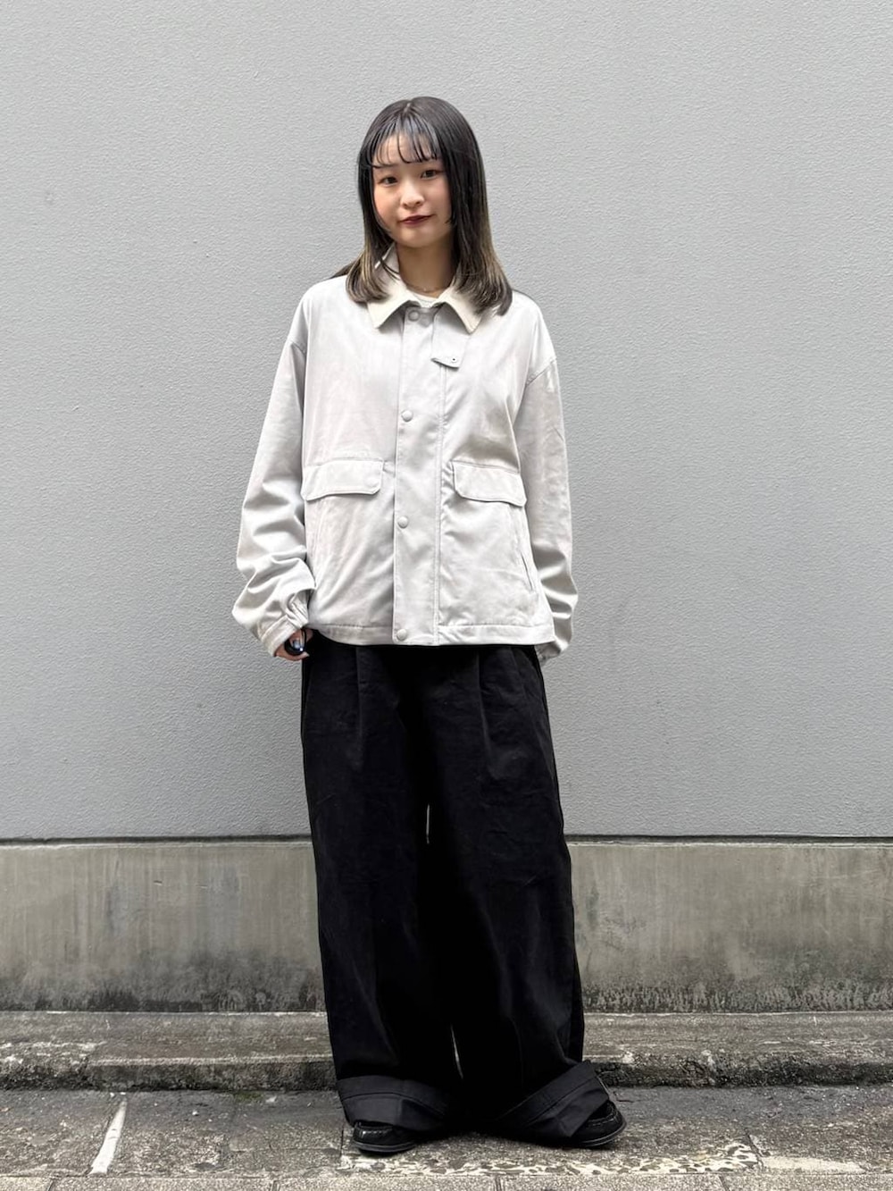 グレー系のブルゾン、ブラック系のチノパンツを着用したレディースの春コーディネートの2枚目の写真