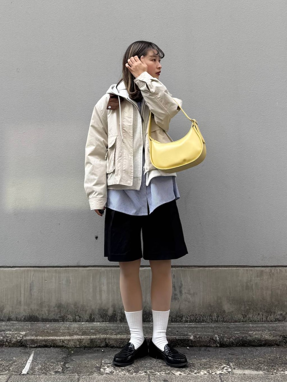 ホワイト系のパーカー、ブラック系のスラックス、イエロー系のショルダーバッグを着用したレディースの春コーディネートの2枚目の写真
