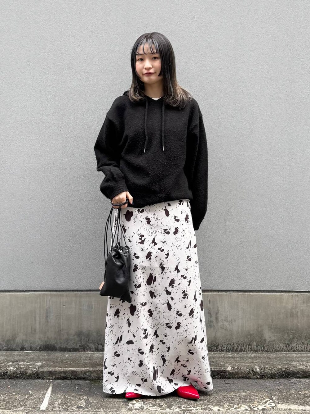 ブラック系のショルダーバッグ、レッド系のパンプス、ブラウン系のスカートを着用したレディースの春コーディネートの2枚目の写真