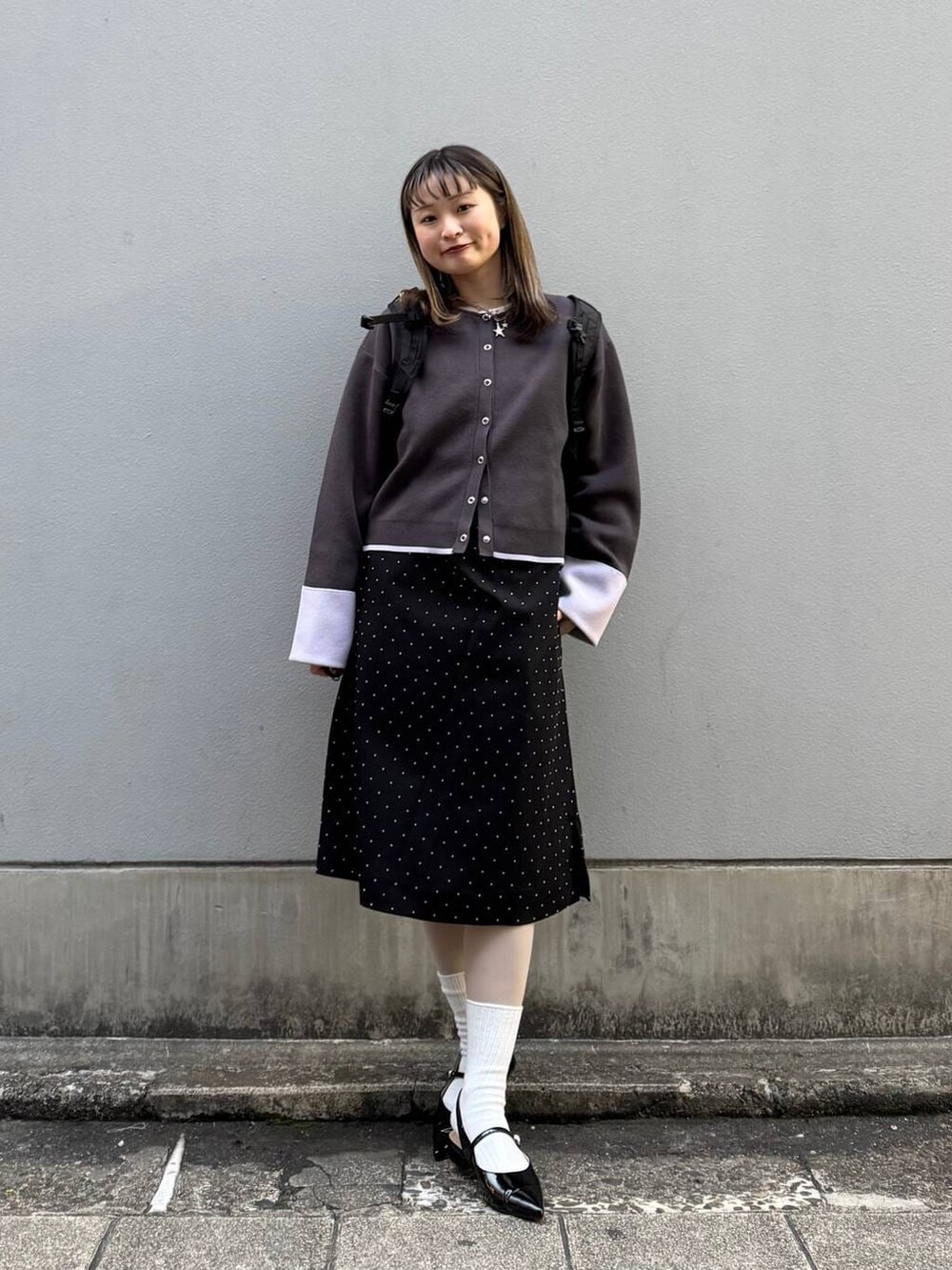 ブラック系のパンプス、グレー系のカーディガン/ボレロ、ブラック系のワンピースを着用したレディースの春コーディネートの3枚目の写真