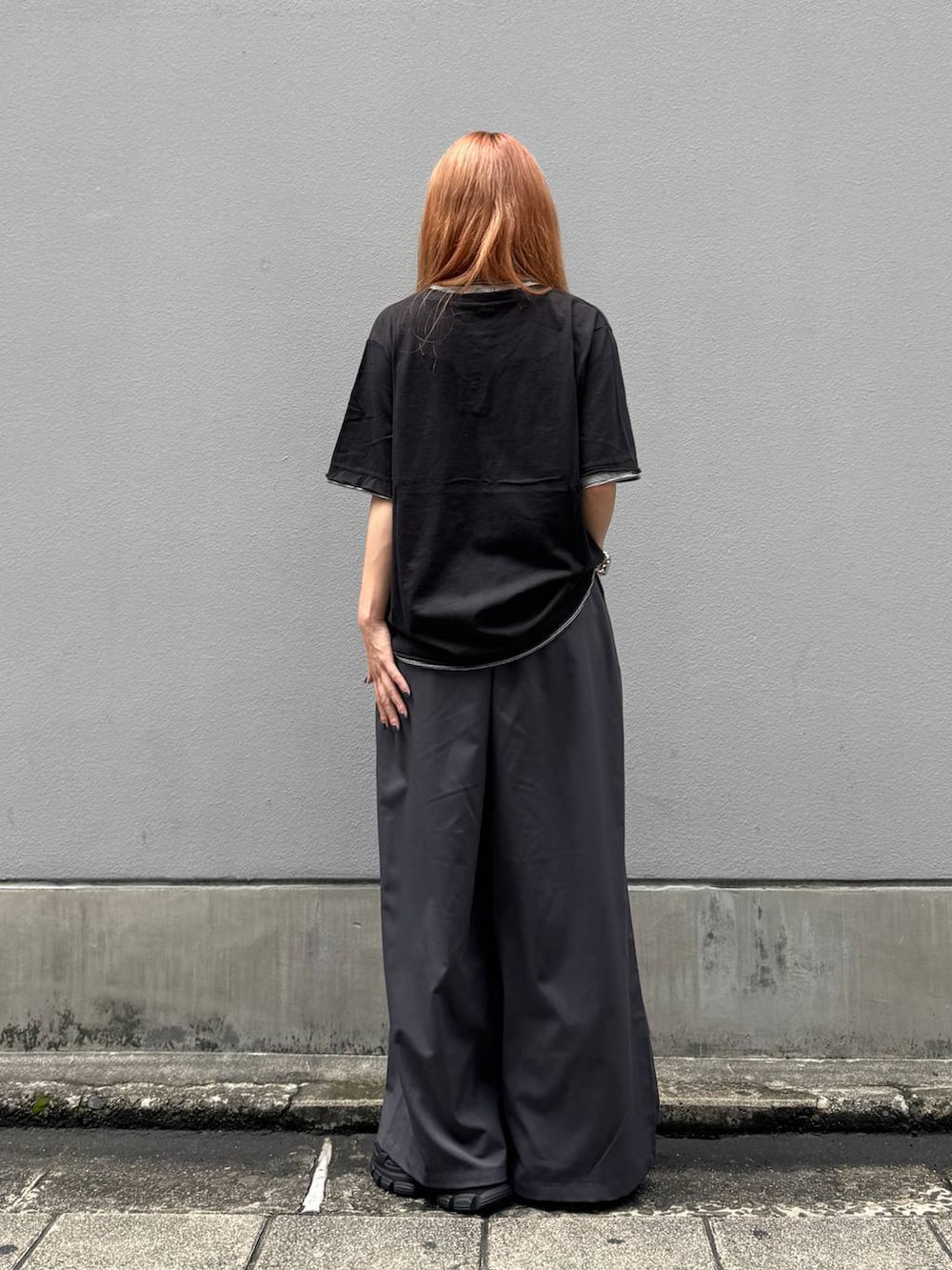 ブラック系のTシャツ/カットソー、グレー系のスラックス、ブラック系のサンダルを着用したレディースの夏コーディネートの6枚目の写真