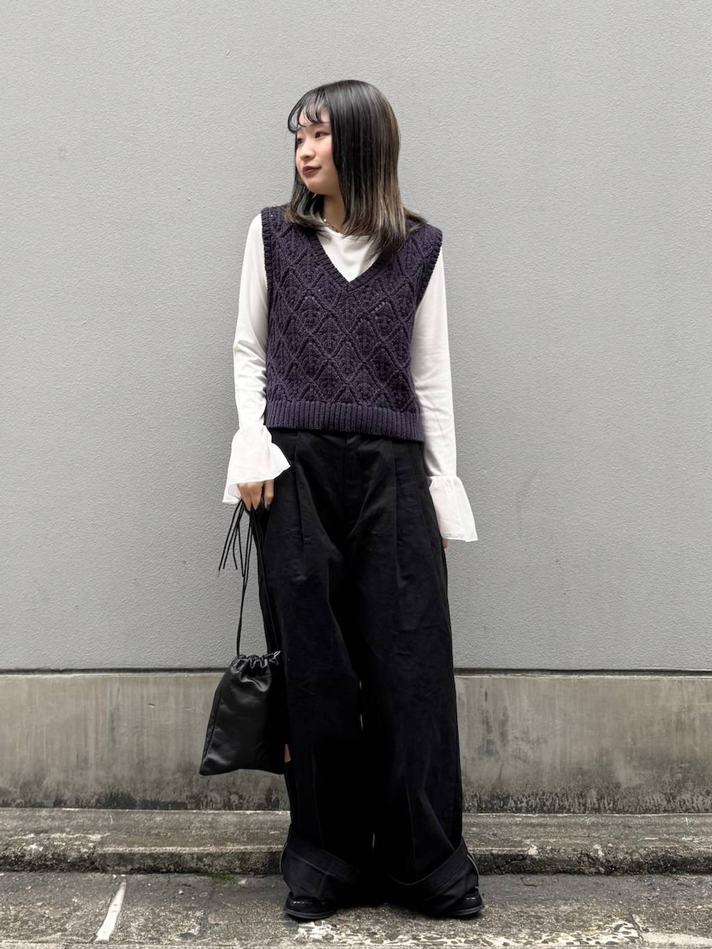 ブラック系のショルダーバッグ、ブラック系のチノパンツ、ホワイト系のTシャツ/カットソーを着用したレディースの春コーディネートの2枚目の写真