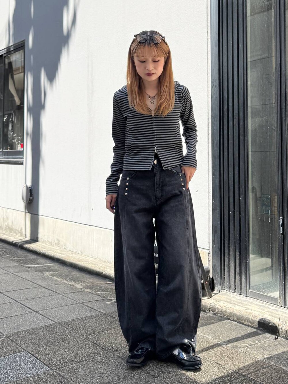 ブラック系のパーカー、グレー系のデニムパンツを着用したレディースの夏コーディネートの4枚目の写真