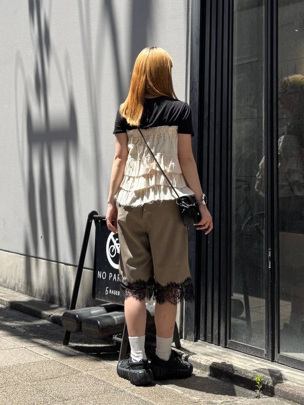 ブラック系のTシャツ/カットソー、ブラック系のショルダーバッグ、ブラウン系のスラックスを着用したレディースの夏コーディネートの5枚目の写真