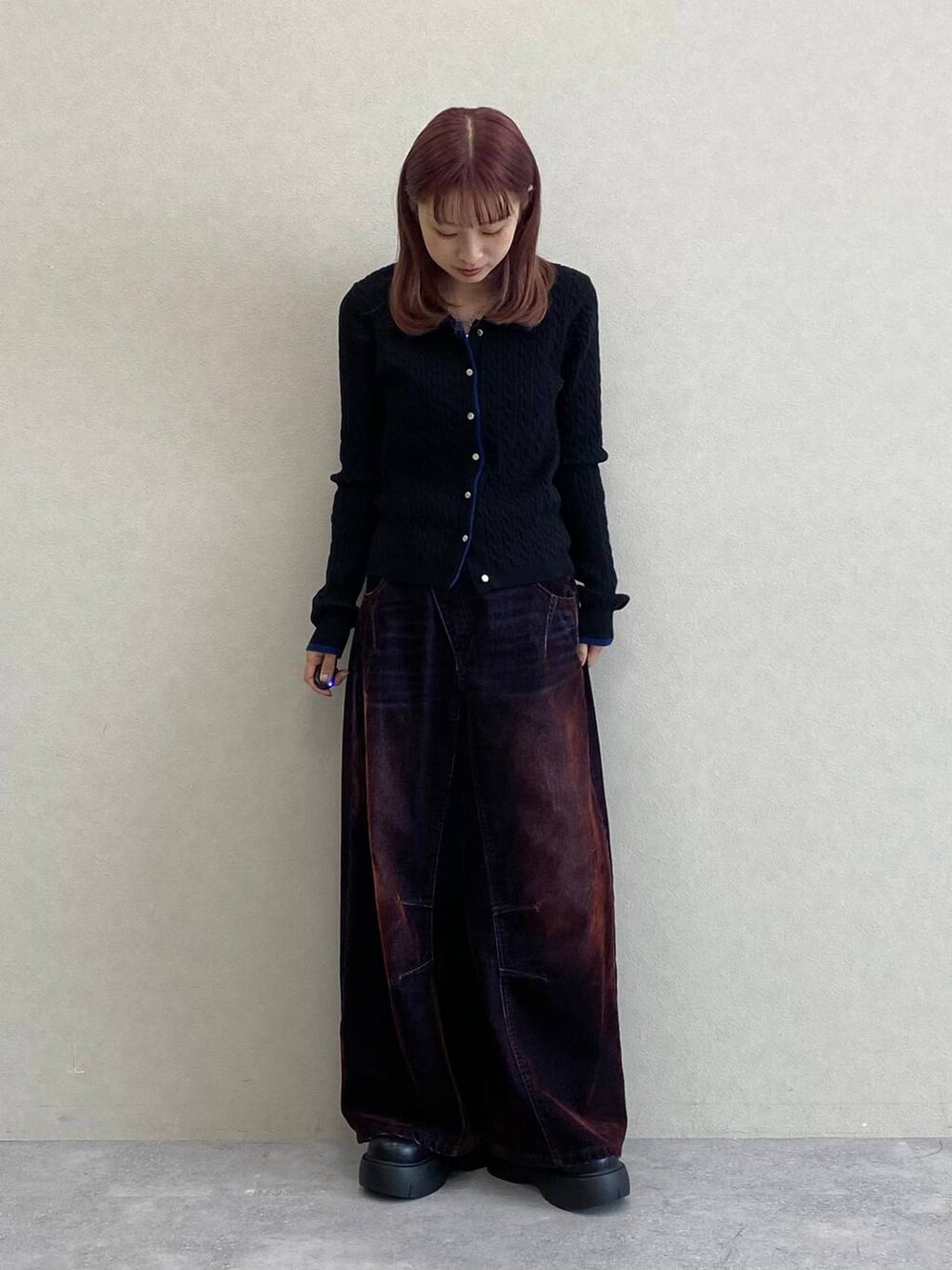 レッド系のデニムパンツ、ブラック系のニット/セーターを着用したレディースの秋コーディネートの2枚目の写真