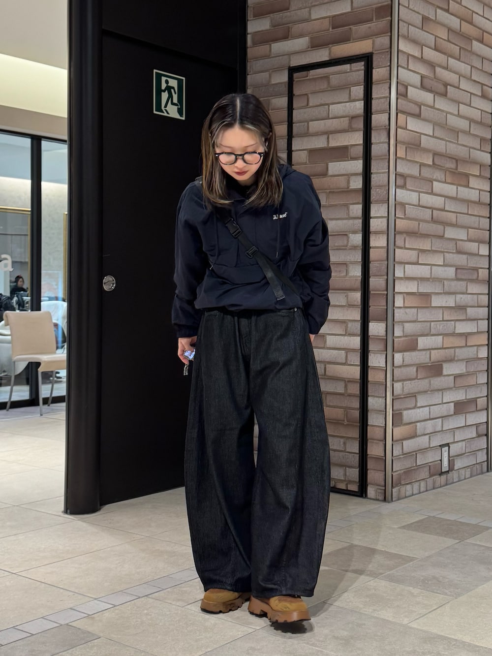 ブルー系のナイロンジャケット、ブラック系のデニムパンツ、ブラウン系のスニーカーを着用したレディースの春コーディネートの4枚目の写真