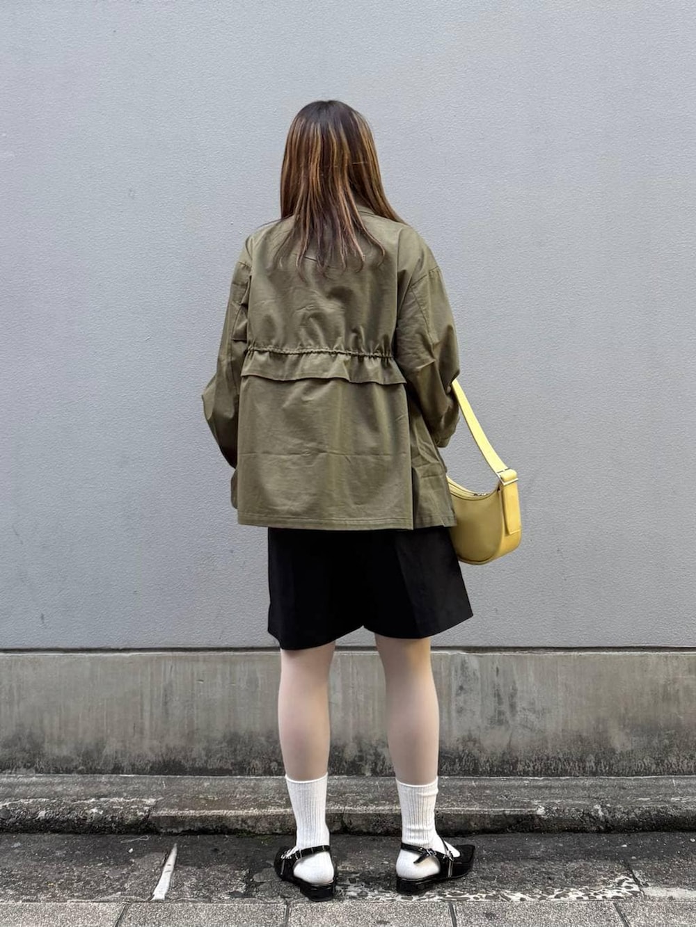 ブラック系のパンプス、ブラック系のスラックス、イエロー系のショルダーバッグを着用したレディースの春コーディネートの5枚目の写真