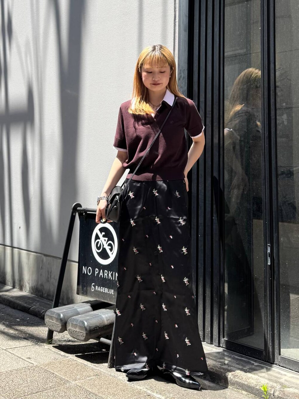 ブラック系のパンプス、ブラック系のスカート、ブラック系のショルダーバッグを着用したレディースの夏コーディネートの4枚目の写真