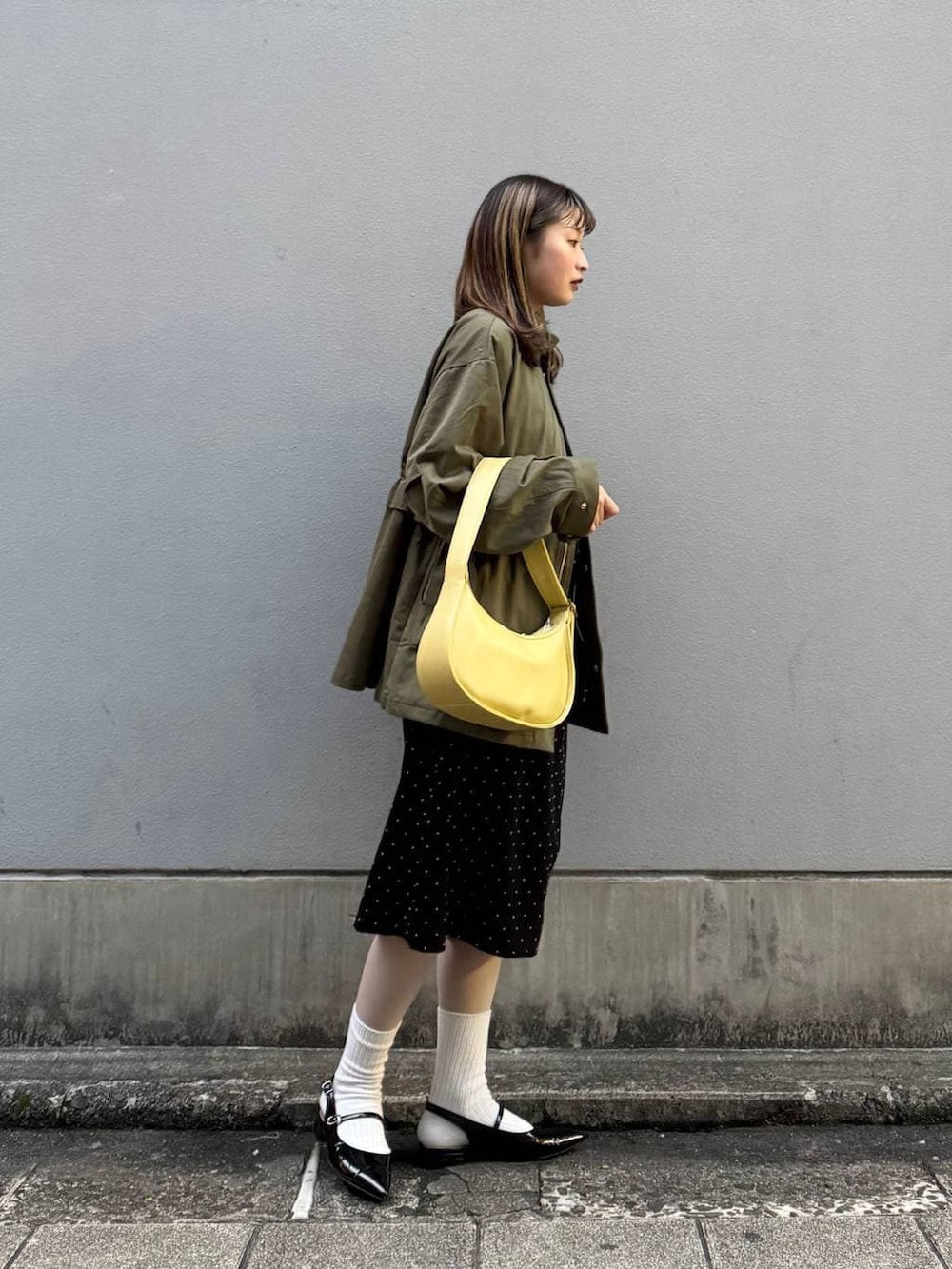 ブラック系のパンプス、イエロー系のショルダーバッグ、ブラック系のワンピースを着用したレディースの春コーディネートの7枚目の写真