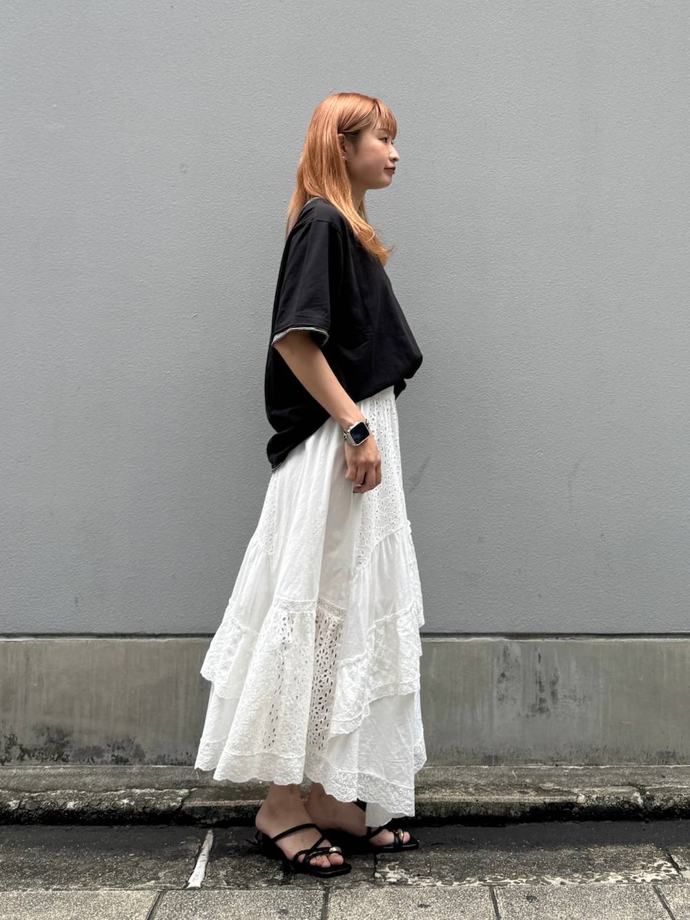ホワイト系のスカート、ブラック系のTシャツ/カットソー、ブラック系のサンダルを着用したレディースの夏コーディネートの6枚目の写真