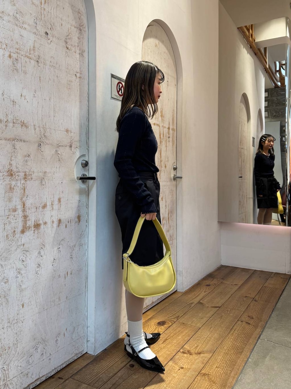 ブラック系のパンプス、ブラック系のスラックス、イエロー系のショルダーバッグを着用したレディースの春コーディネートの7枚目の写真