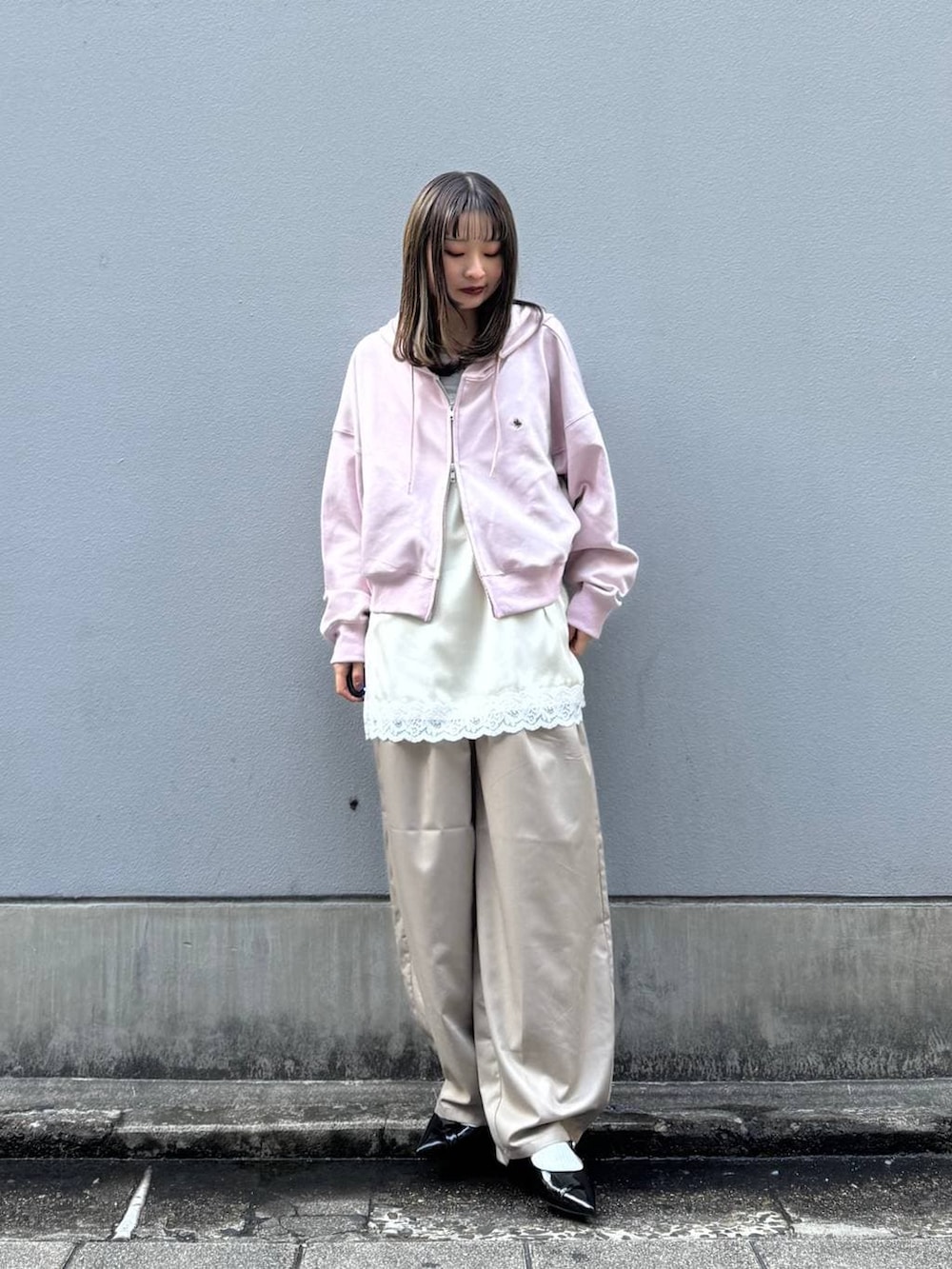 ブラック系のパンプス、ホワイト系のキャミソール、ベージュ系のスラックスを着用したレディースの春コーディネートの2枚目の写真