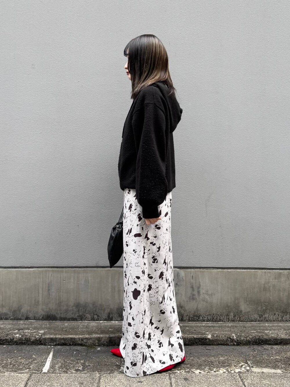 ブラック系のショルダーバッグ、レッド系のパンプス、ブラウン系のスカートを着用したレディースの春コーディネートの5枚目の写真