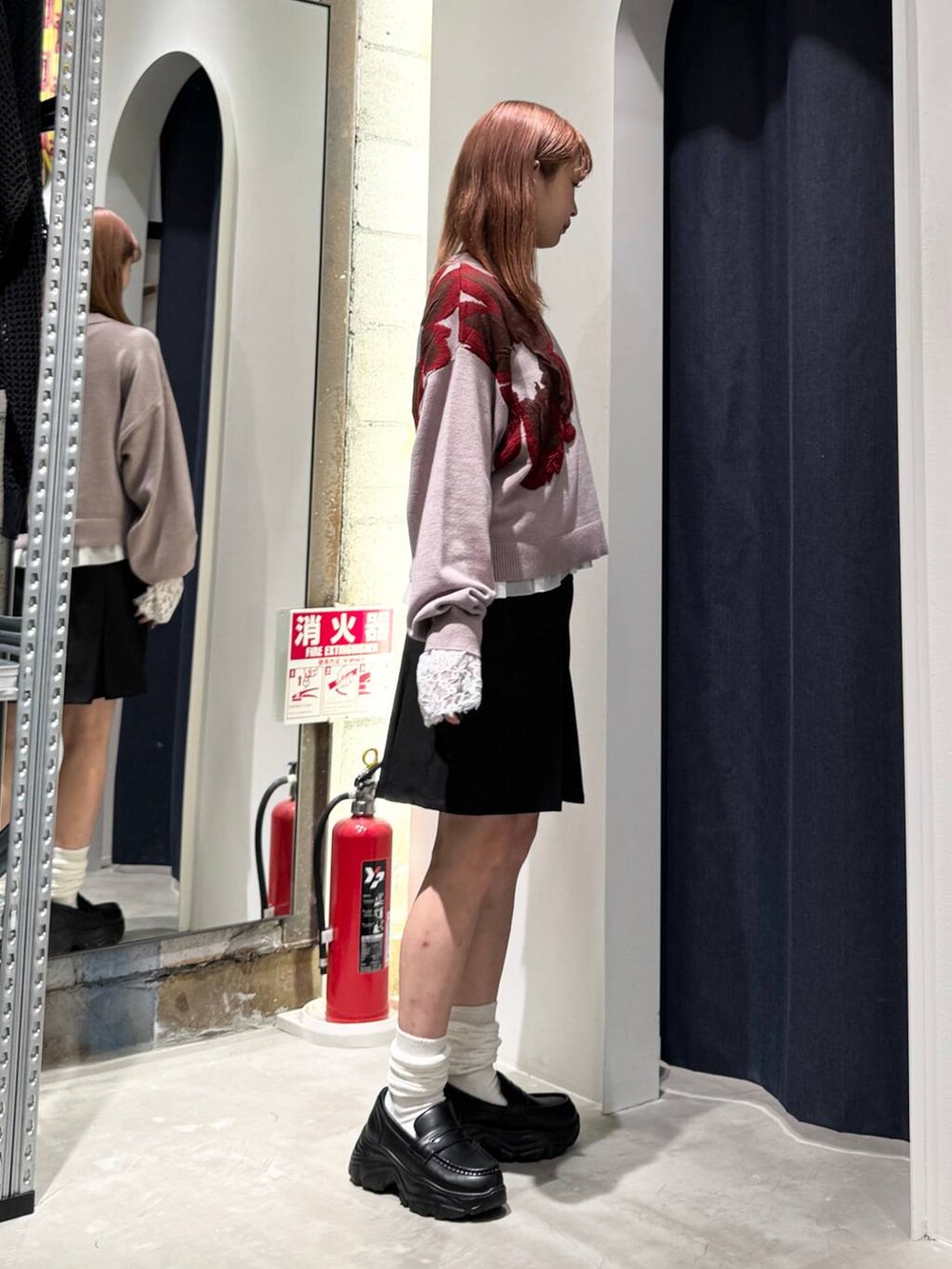 ホワイト系のTシャツ/カットソー、ピンク系のニット/セーター、ブラック系のスカートを着用したレディースの秋コーディネートの6枚目の写真