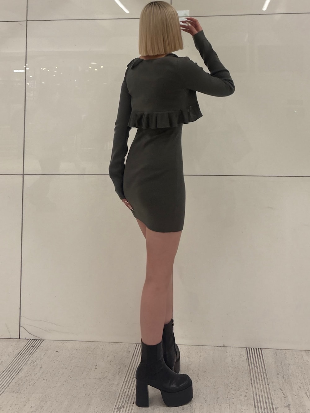 グレー系のワンピース、ブラック系のブーツを着用したレディースの冬コーディネートの2枚目の写真