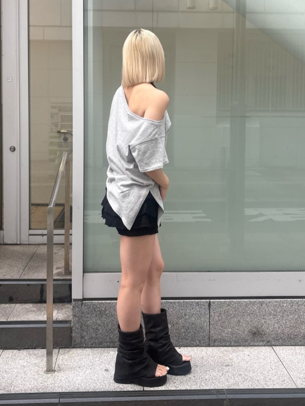 ブラック系のスカート、ブラック系のサンダル、グレー系のTシャツ/カットソーを着用したレディースの夏コーディネートの2枚目の写真