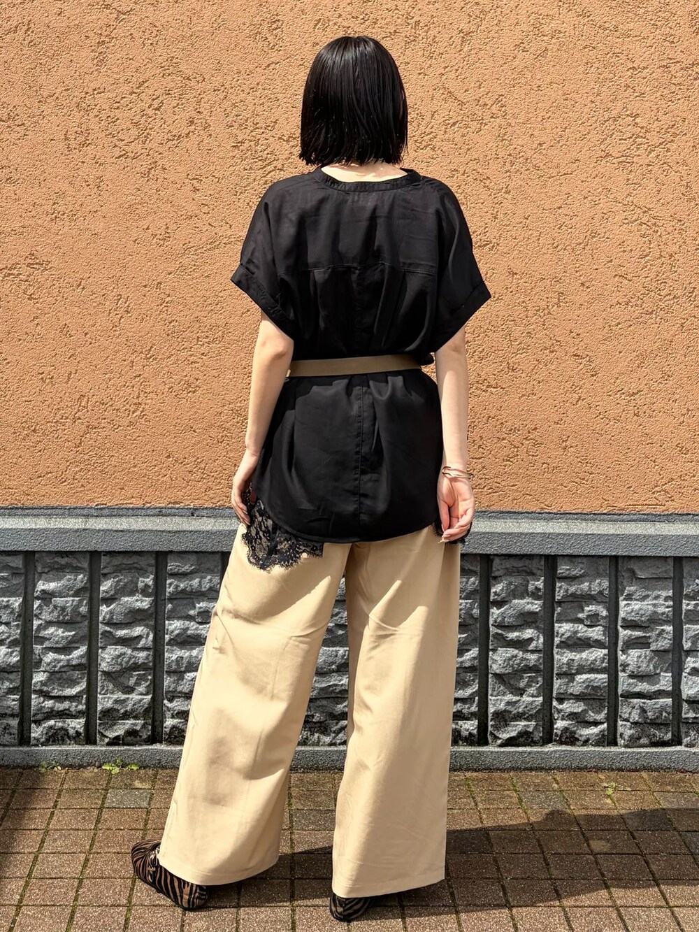 ベージュ系のスラックス、ブラック系のシャツ/ブラウス、ブラック系のキャミソールを着用したレディースの春コーディネートの3枚目の写真