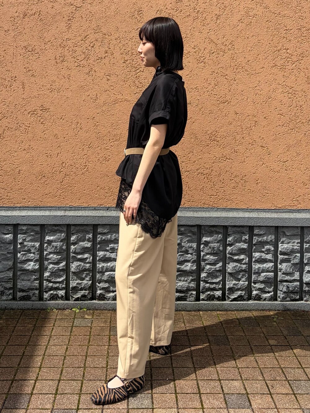 ベージュ系のスラックス、ブラック系のシャツ/ブラウス、ブラック系のキャミソールを着用したレディースの春コーディネートの2枚目の写真