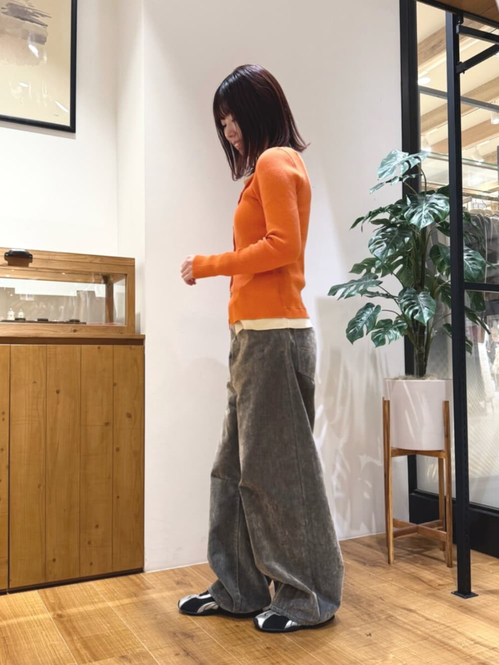ベージュ系のデニムパンツ、オレンジ系のカーディガン/ボレロを着用したレディースの秋コーディネートの2枚目の写真