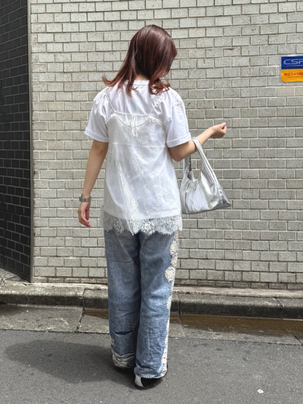 シルバー系のハンドバッグ、ブルー系のデニムパンツ、ホワイト系のキャミソールを着用したレディースの夏コーディネートの3枚目の写真