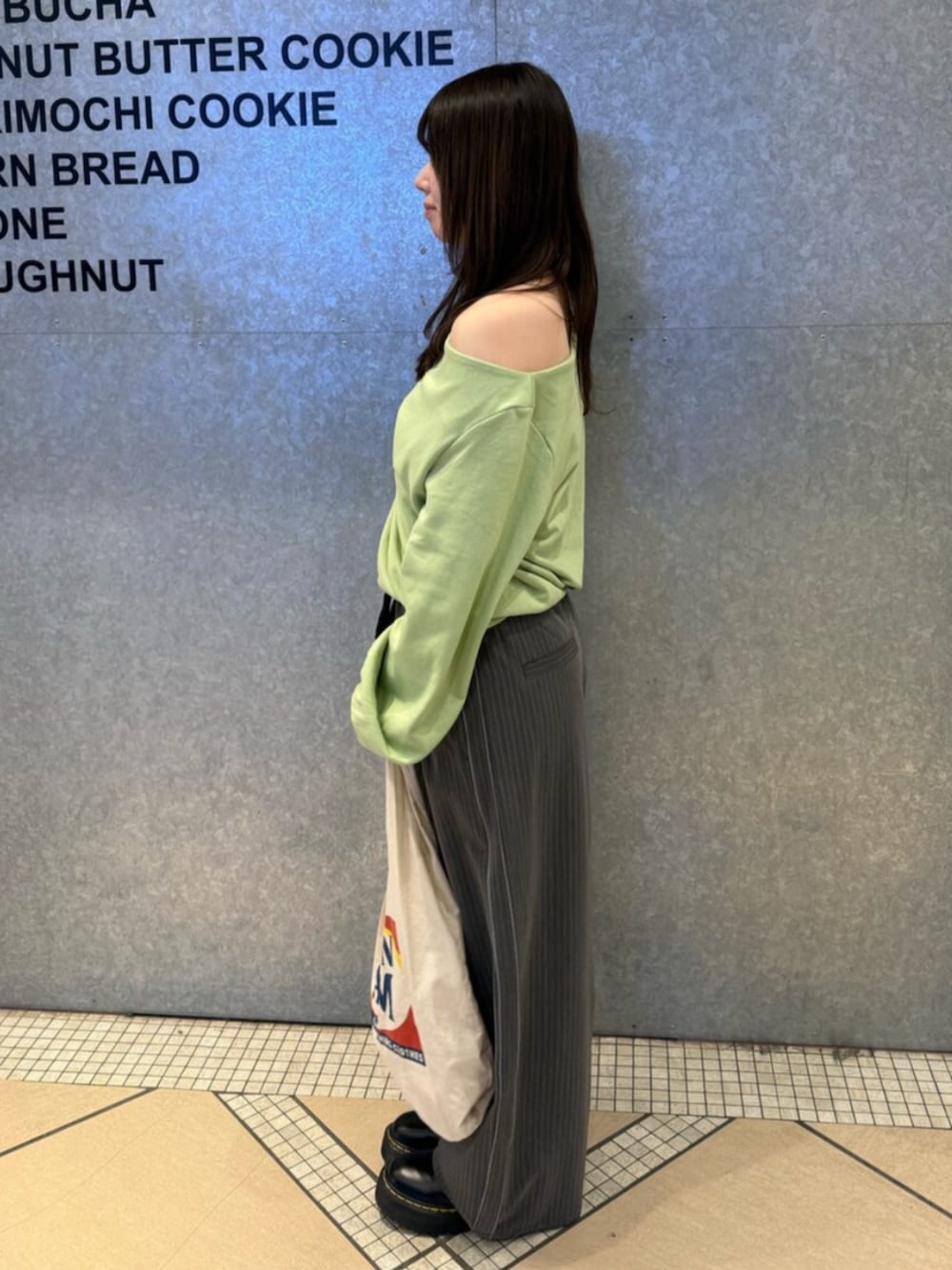 グリーン系のTシャツ/カットソー、グレー系のその他パンツ、ホワイト系のトートバッグを着用したレディースの冬コーディネートの2枚目の写真